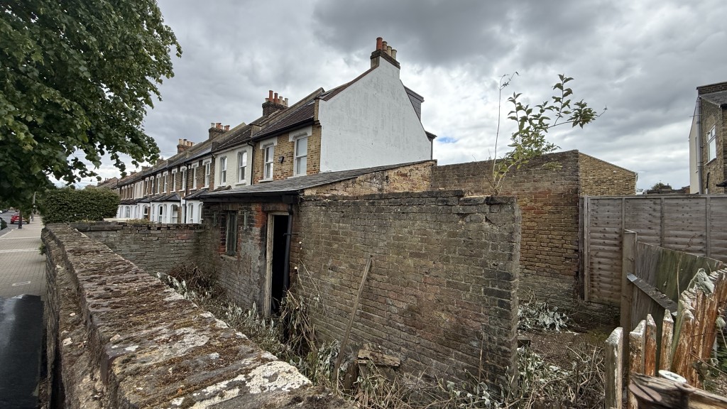 Lot: 62 - PARCEL OF LAND WITH EXISTING OUTBUILDING - External image of building over wall from end